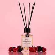 Difusor de aroma wild berries 110 ml con varillas sobre fondo rosa, rodeado de frutos rojos.