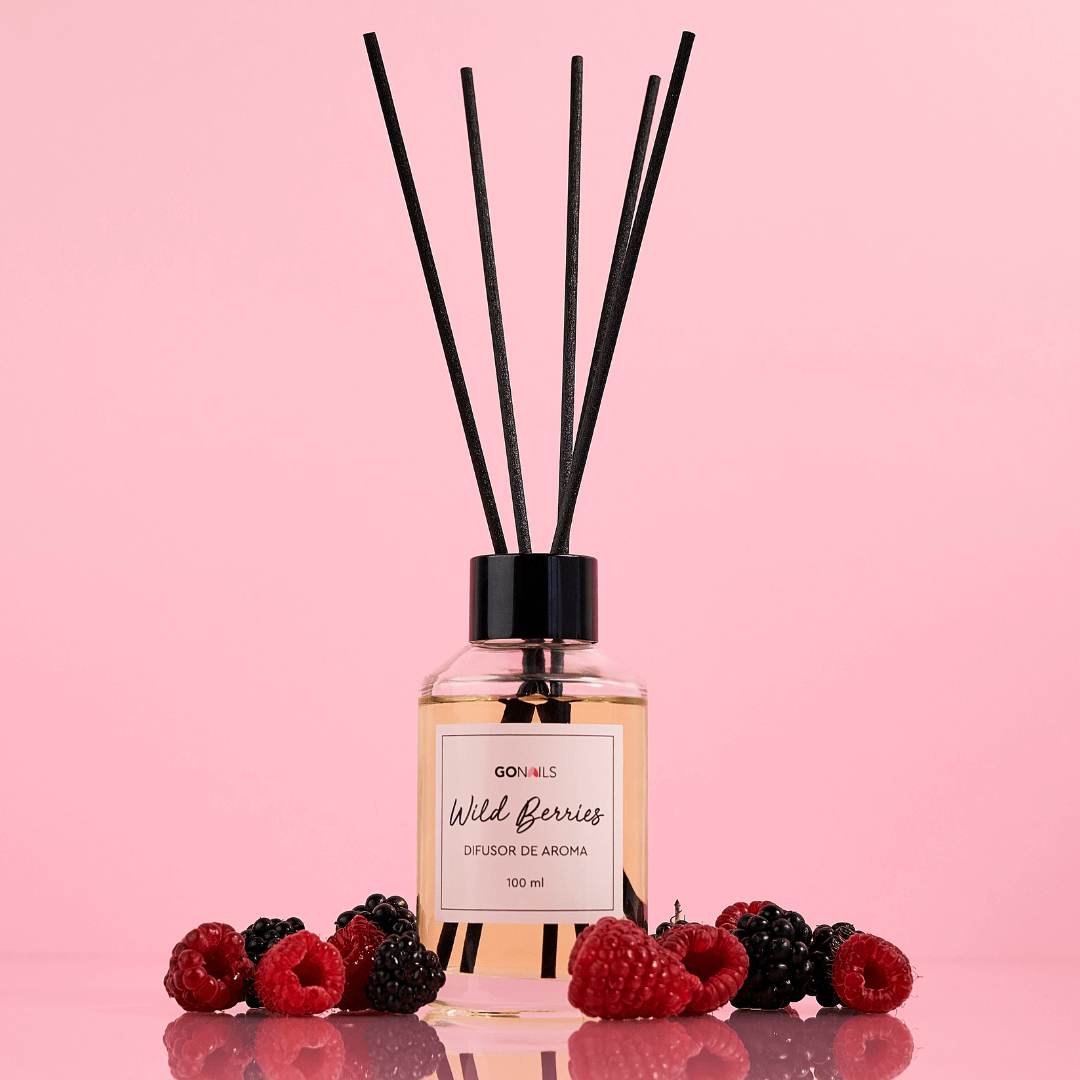 Difusor de aroma wild berries 110 ml con varillas sobre fondo rosa, rodeado de frutos rojos.
